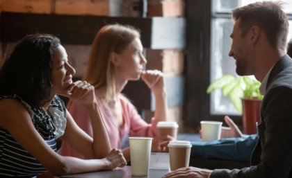 A woman sitting across from a man at a table, the man looks as though he is laughing while the woman is smiling